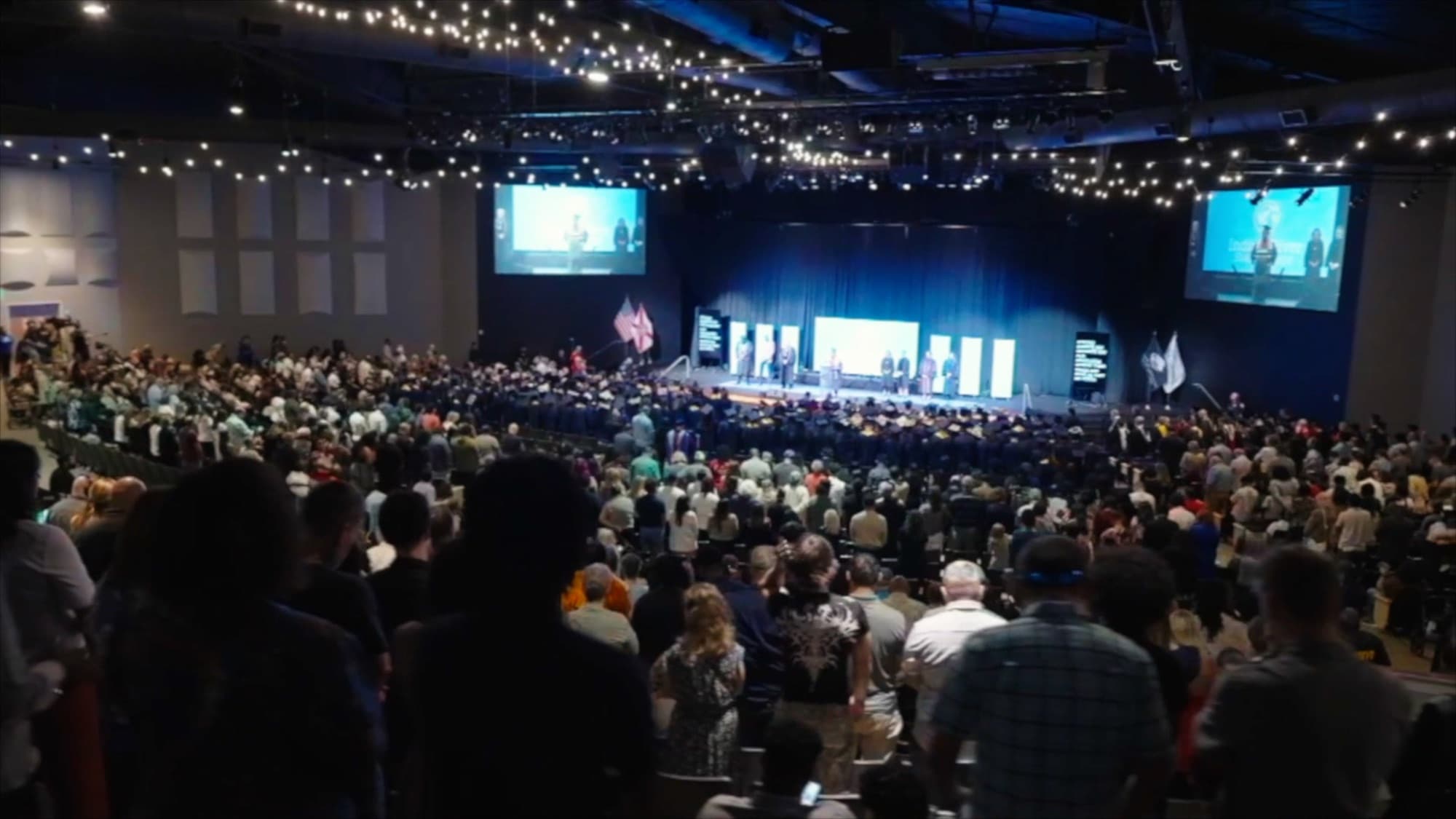 Wide shot of the full commencement crowd and stage screens